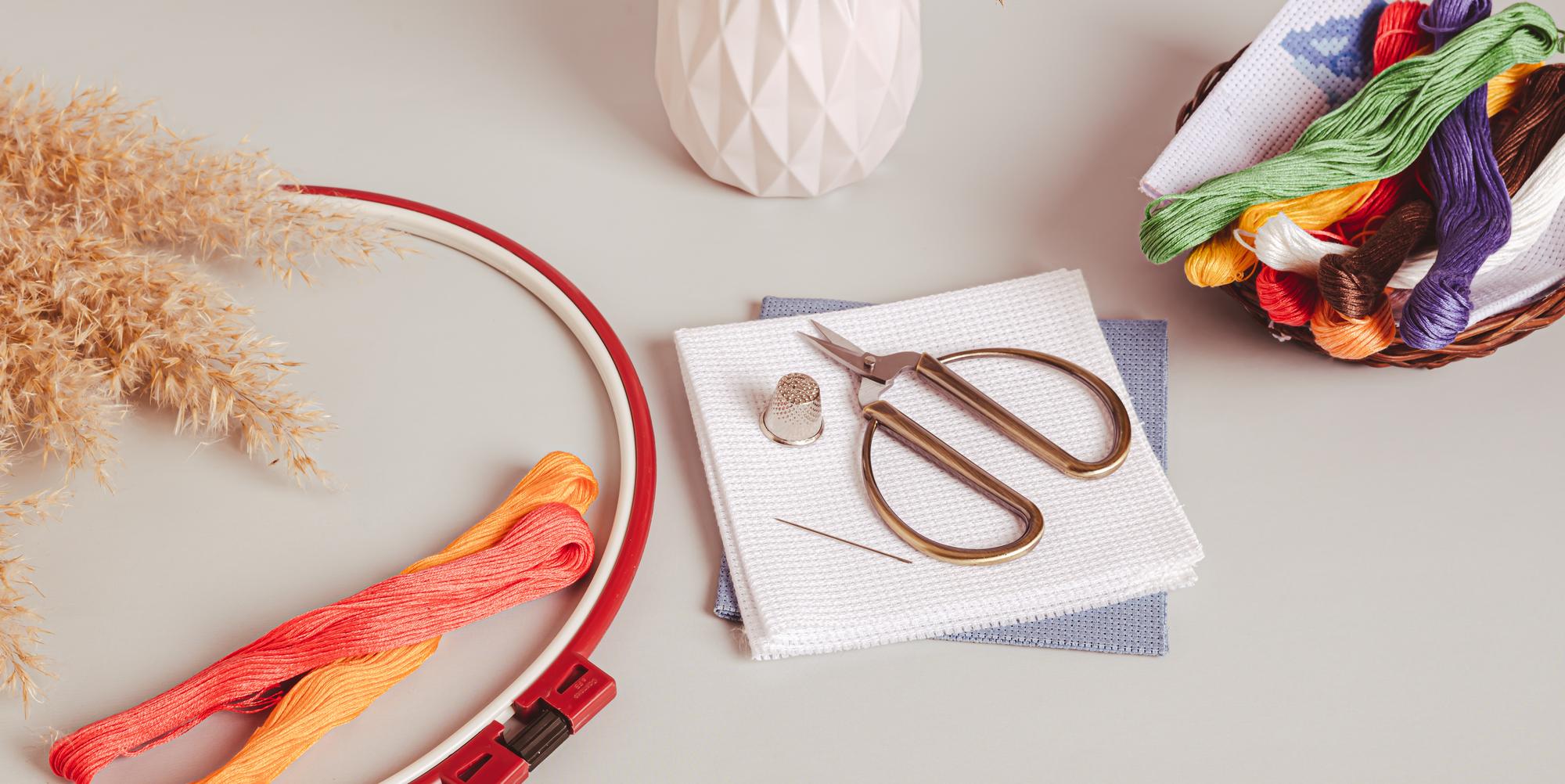 Workspace with hoop, thread and scissors on wooden table